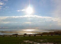 Die untergehende Sonne bescheint die Wasserpfützen auf dem trockengefallenen Strand auf Terschelling