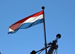 Die niederländische Flagge im Großmast der Banjaard weht im Wind vor einem strahlend-blauen Himmel ohne Wolken.