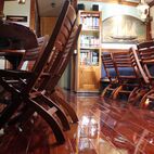 Ein gemütlicher Salon mit spiegelnd-lackiertem Holzfussboden, stapelbaren Stühlen, einem Bücherregal und Dekor im nautischen Stil.
