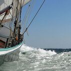 Das Segelschiff Banjaard schneidet durch die Wellen, die Bugwelle schäumt und wird am Rumpf vorbei gedrückt - das Rauschen ist beinah hörbar und die Bewegung spürbar