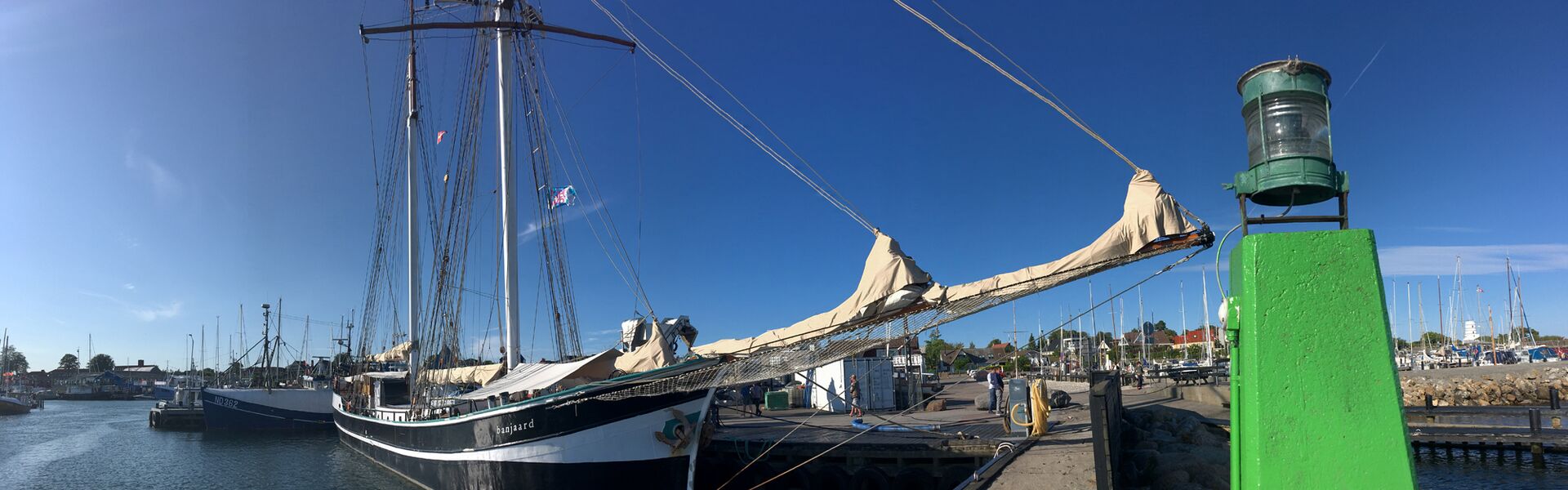 Das Segelschiff Banjaard auf dem wohl kleinst möglichen Liegeplatz: der Klüverbaum ragt über den Steg, über den Zaun hinaus und ist nur um. Zentimeter an dem grünen Pfahl mit dem Licht der Hafeneinfahrt vorbeigekommen