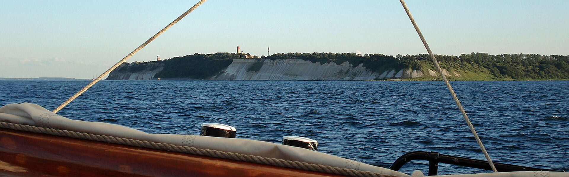 Im Vordergrund ist noch ein eingepacktes Segel zu sehen. Im Hintergrund füllen die Steilküste von Rügen mit den Kreidefelsen das Bild, darüber en fahlblauer Himmel.