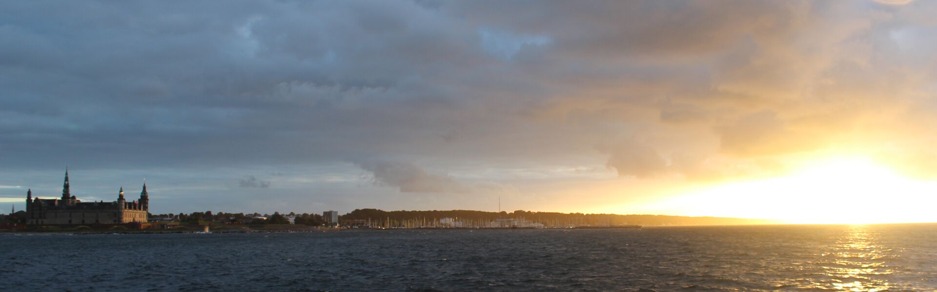 Schloss Helsingør am Öresund vom Wasser aus gesehen im dramatischen Licht eines Sonnenuntergangs kurz nach einem Gewitter.
