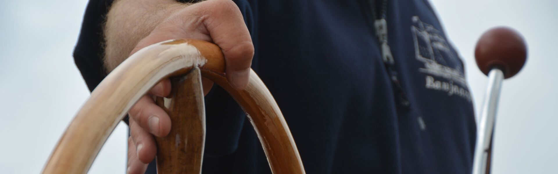 Die Hand des Kapitäns hält das Steuerrad der Banjaard.